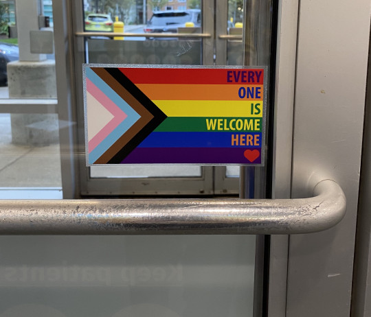 Pride flag on door frame. Everyone is Welcome Here.