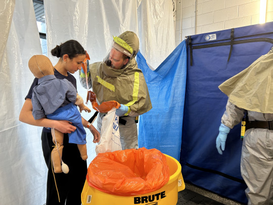 Decontamination trainee help simulation patient with simuation doll