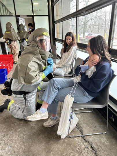 Student simulates as a patient mother with a baby doll with a caregiver in a hazmat suite
