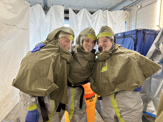 Three decontamination trainees post in hazmat suits