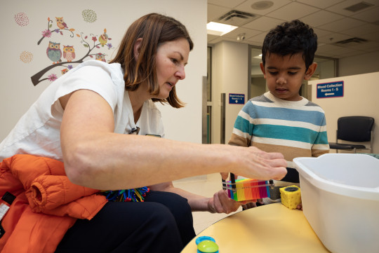 A nurse and child look at a toy together.