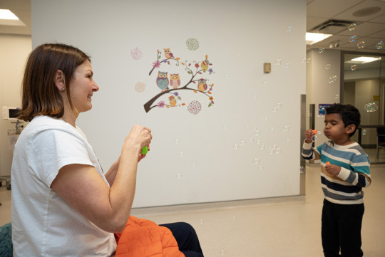 A nurse and child blow bubbles.