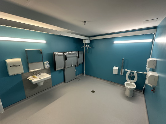 A large open  bathroom with light blue walls and accessible equipment