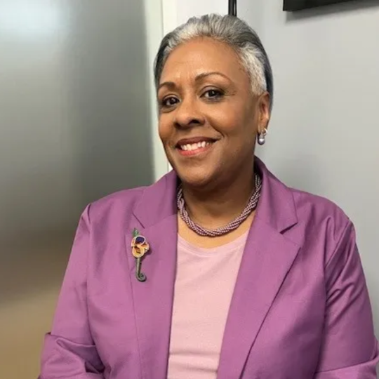 Angela Johnson in a purple suit, smiling at the camera. 