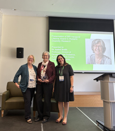 Dr. Isabel Smith stands in the middle of a trio holding an award.
