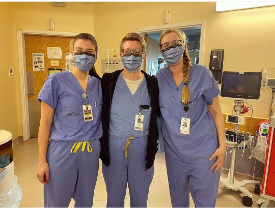 Three midwives stand in scrubs.