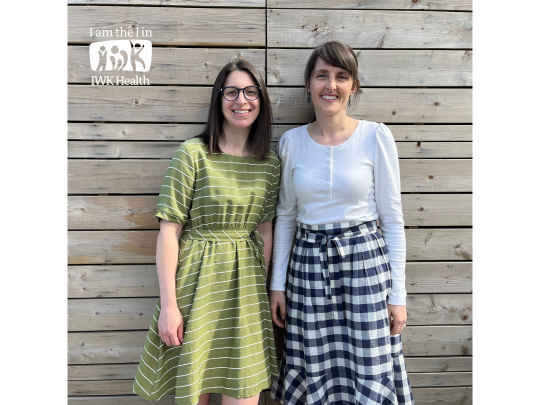 Drs. Angela Giacomantonio and Rachel Shaw stand in front of a wooden fence.