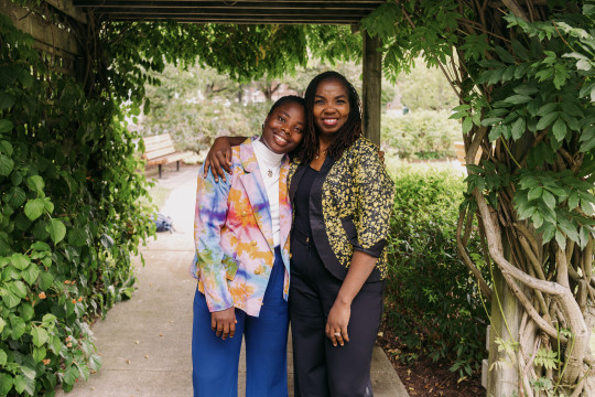 Barbara Blays and Afolake Awoyiga stand under a leafy awning.