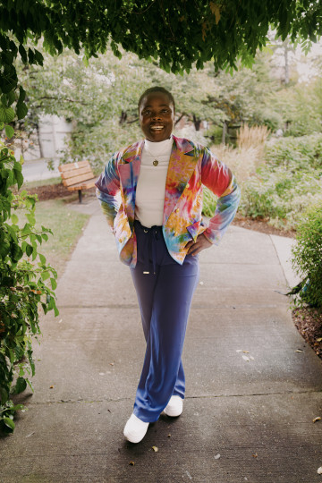 Barbara Blays in colourful jacket stand under a leafy awning.