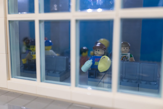 A LEGO mini figure father holds a baby and bottle.