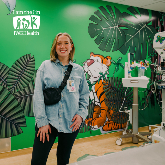 Thea Fynes stands in the MRI room, a colourful tiger and jungle motif on the wall.