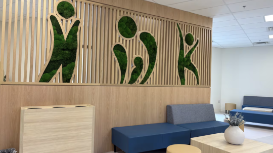 The lobby of the new clinic with blue couches and IWK written on the wall in living plants.