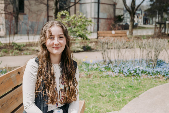 Tori Sabean sits on a park bench on a sunny day.