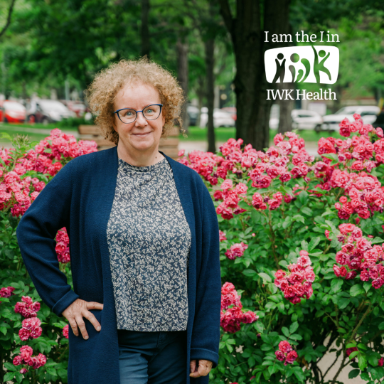 Theresa Pickart stand in the Newman gardens surrounded by flowers.
