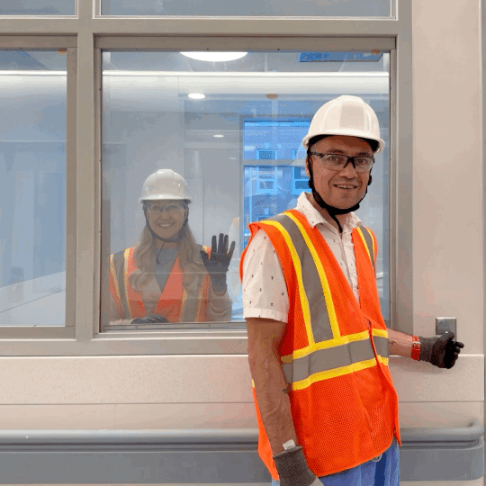 Brian flicks a switch that makes the window opaque and then back again with Katie visible behind the glass.