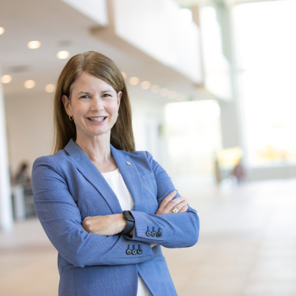 Monica Foster standing with arms crossed wearing a blue blazer