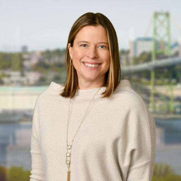 Lindsay Hawker smiling in front of the harbour and bridge wearing a cream sweater