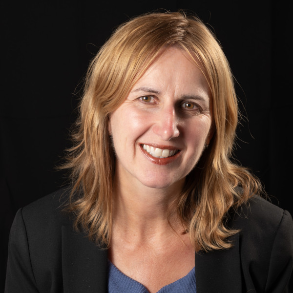 Woman smiling with black jacket over blue shirt