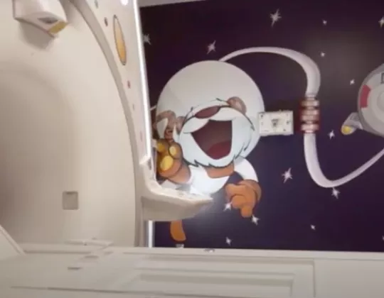 MRI machine in front of wall painted with cartoon of a tiger astronaut floating in space