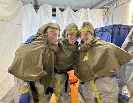 Three decontamination trainees post in hazmat suits