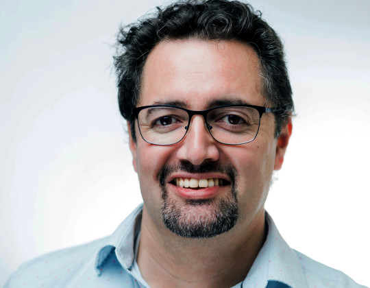 Doctor Victor Martinez wears glasses and a blue collared shirt.