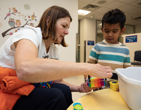 A nurse and child look at a toy together.