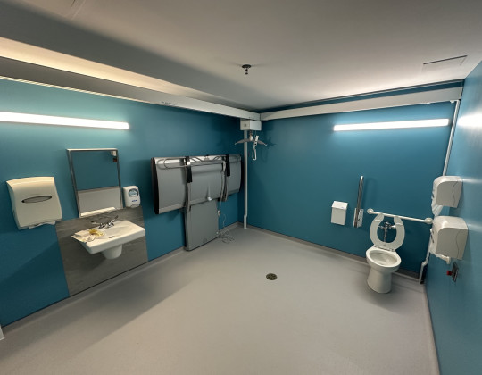 A large open  bathroom with light blue walls and accessible equipment