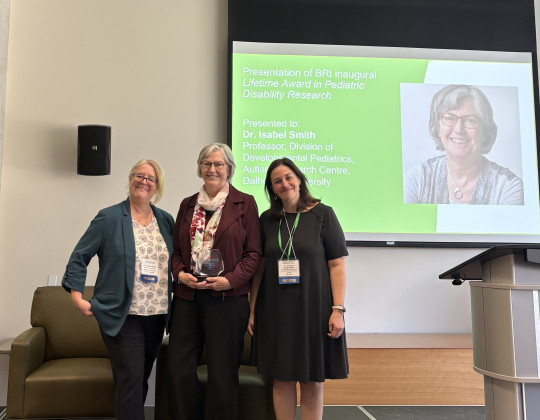 Dr. Isabel Smith stands in the middle of a trio holding an award.