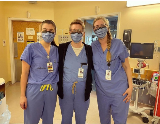Three midwives stand in scrubs.