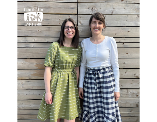 Drs. Angela Giacomantonio and Rachel Shaw stand in front of a wooden fence.