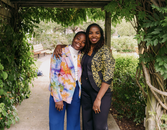 Barbara Blays and Afolake Awoyiga stand under a leafy awning.