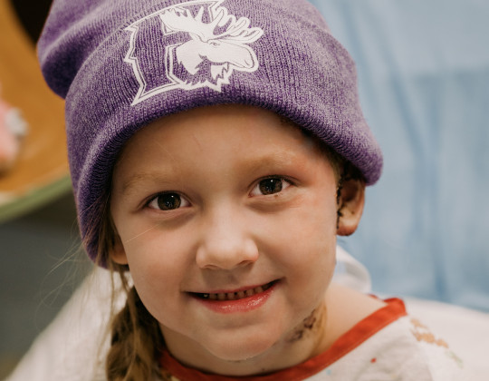 Addy Dodge sits in a hospital bed wearing a purple Mooseheads toque.