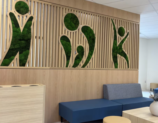 The lobby of the new clinic with blue couches and IWK written on the wall in living plants.