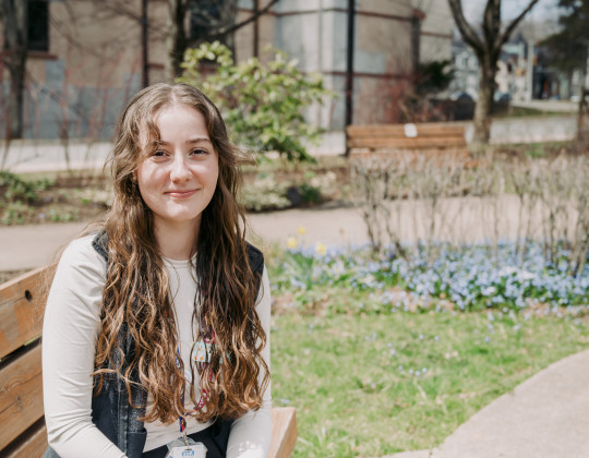 Tori Sabean sits on a park bench on a sunny day.