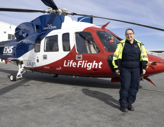 Respiratory therapist Jessica Carew stand beside a LifeFlight helicopter.